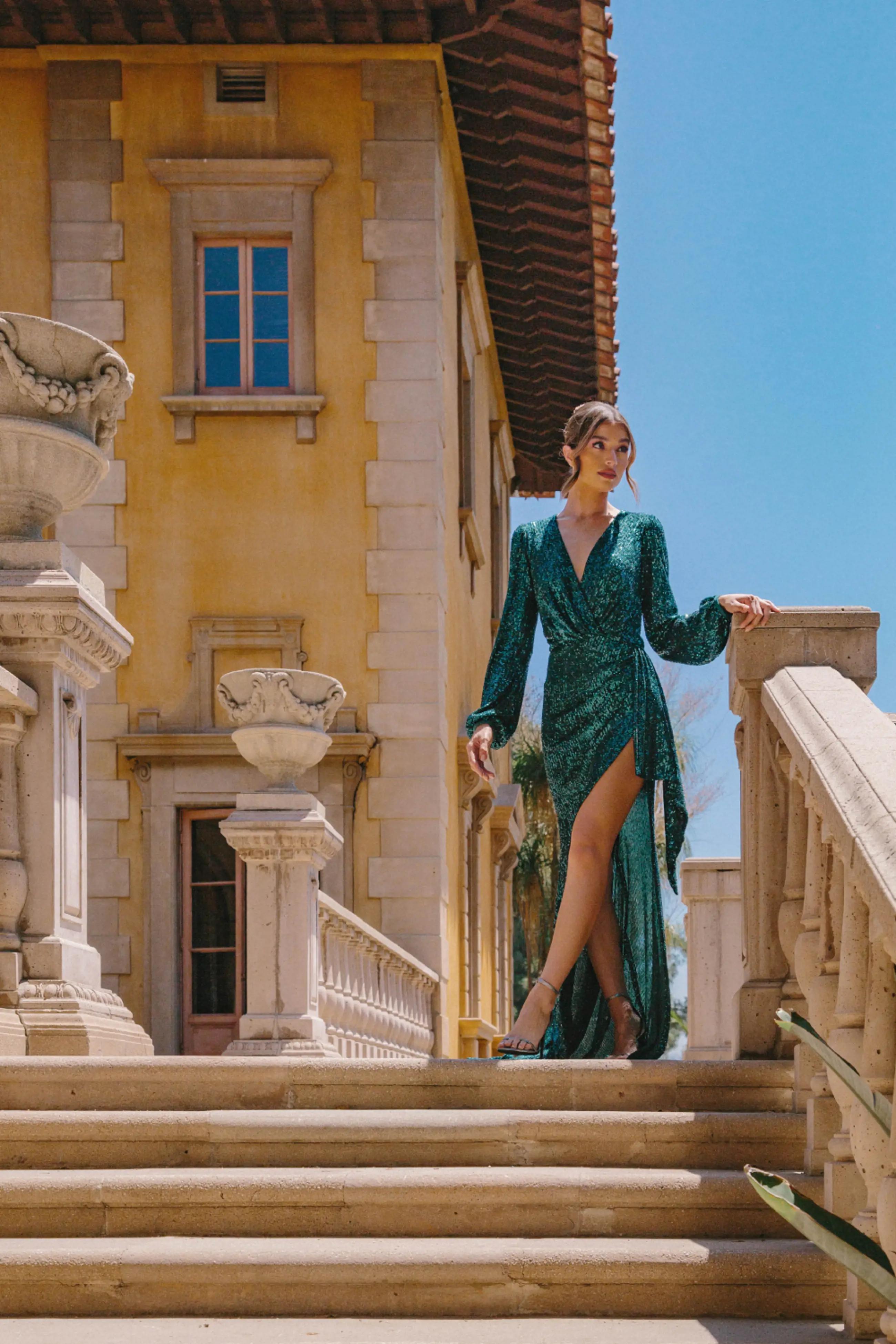 Model wearing a green evening gown near the building