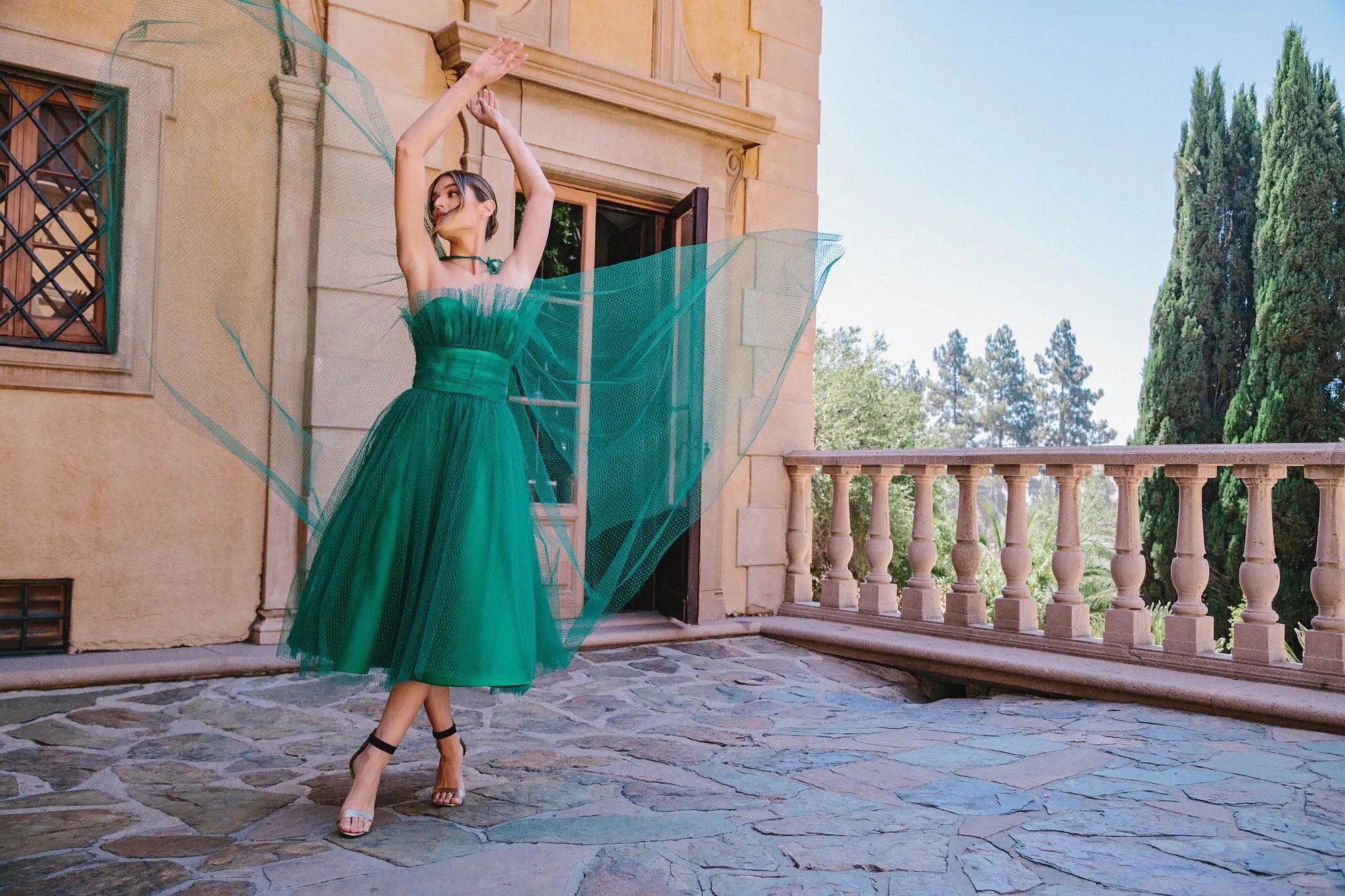 Model wearing a green evening gown near the building