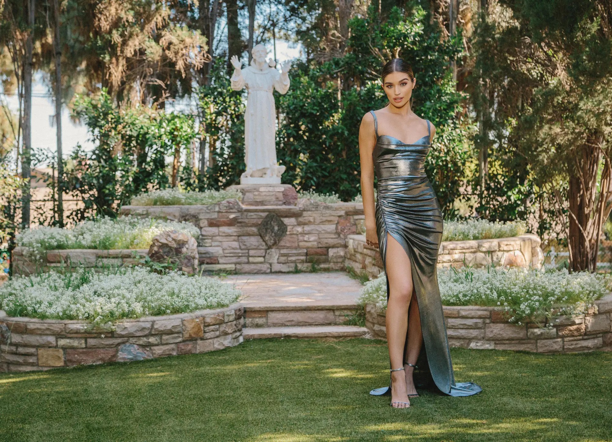 Model wearing a long silver evening gown near the monument