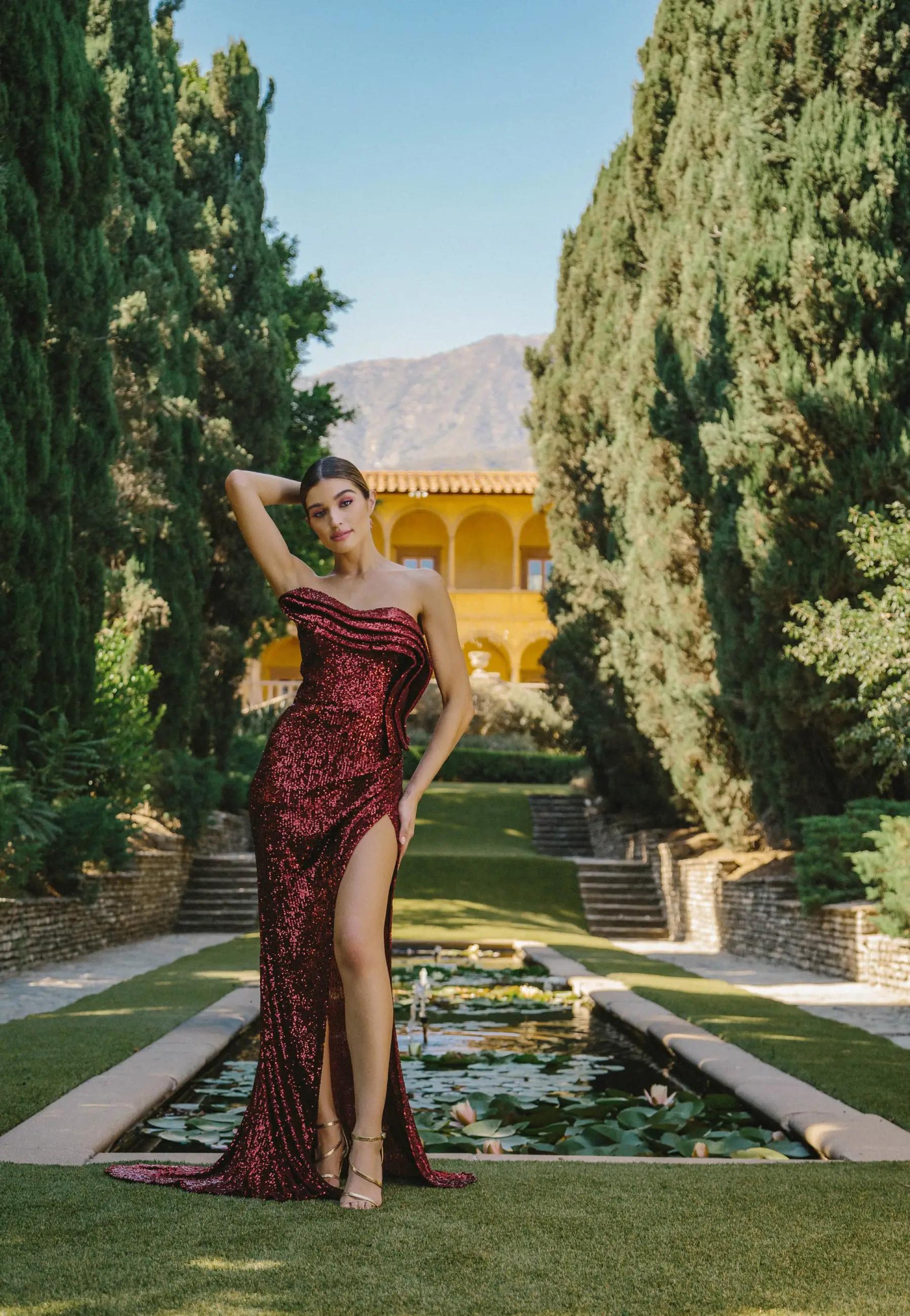 Model wearing a long red evening gown near the fountain